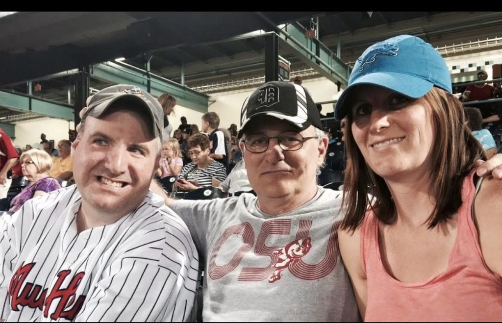 Three people smile for a selfie at a baseball game.