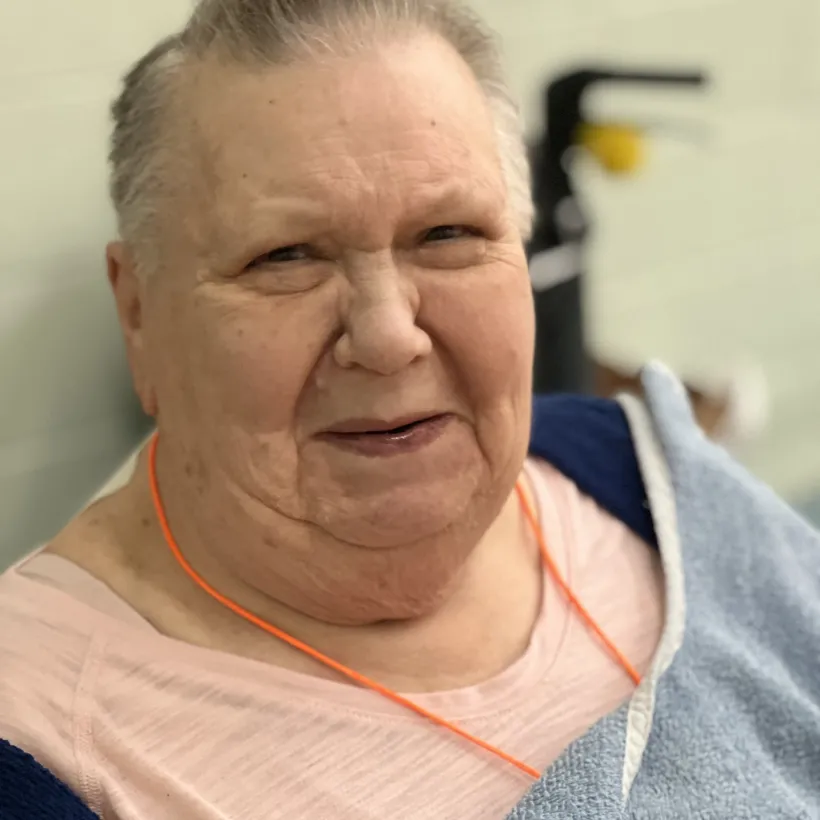Portrait of a smiling elderly woman wrapped in a towel at Sunshine Communities, representing warmth, comfort, and personalized support in residential care.