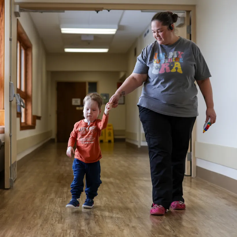 A child and their caregiver walking down a hall